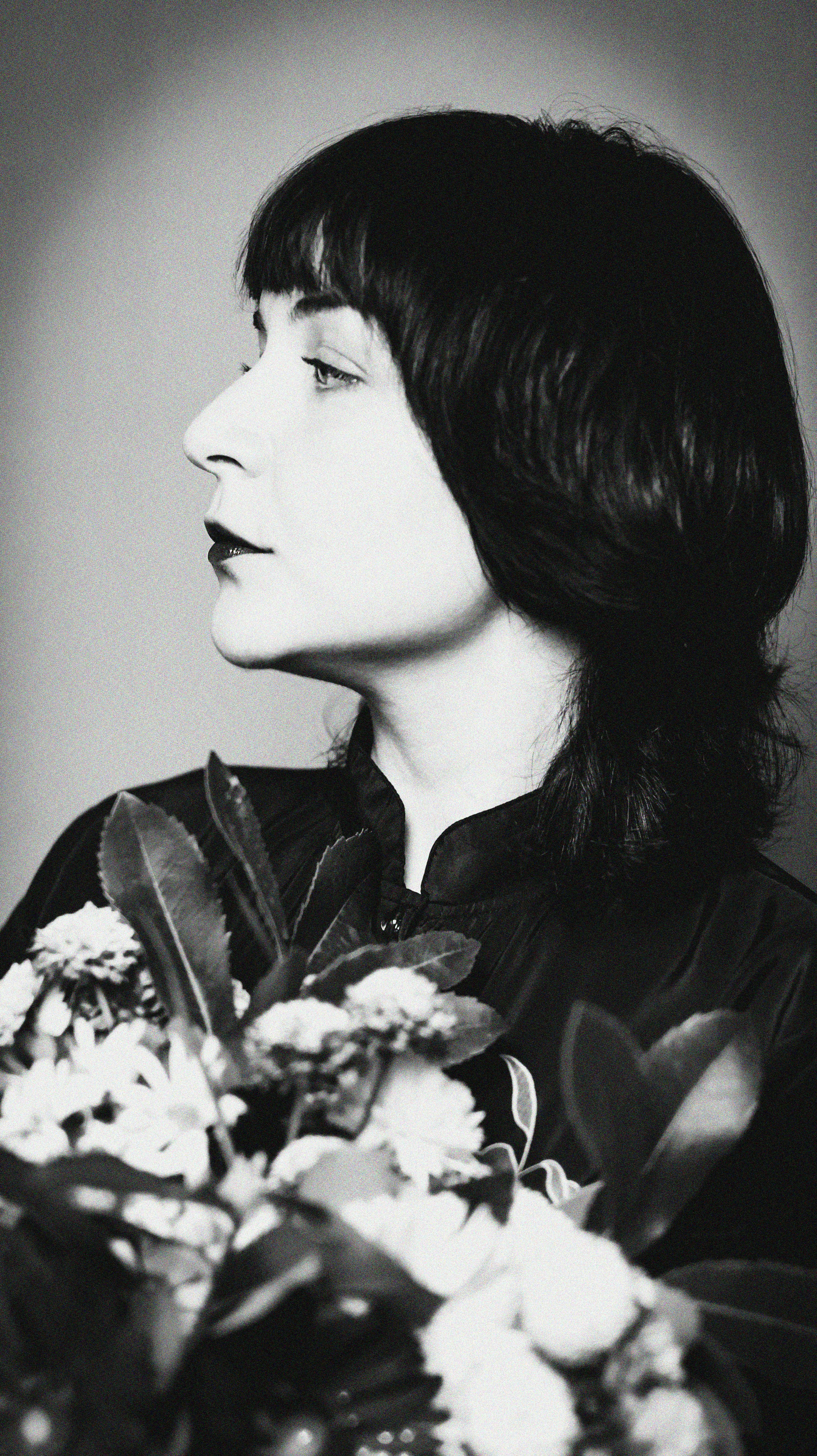 Elegant black and white profile portrait of a woman holding flowers.
