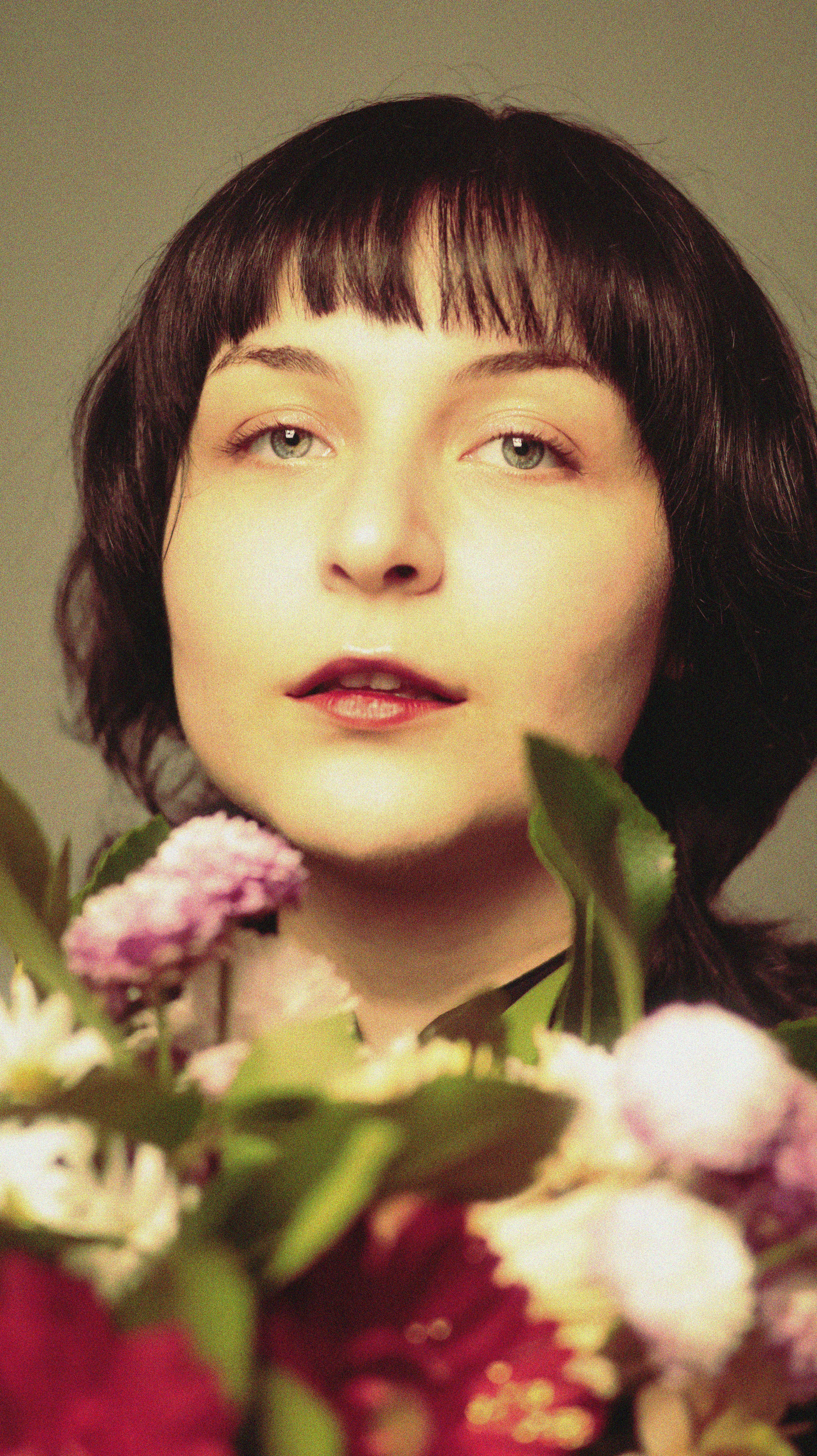 Elegant portrait of a woman surrounded by vibrant summer flowers.
