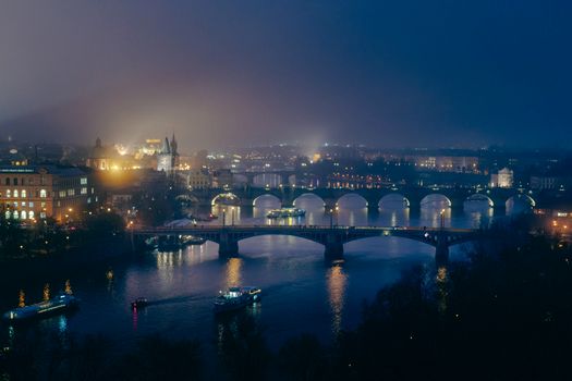 Stunning night view of Prague featuring illuminated bridges and city lights reflecting off the Vltava River.