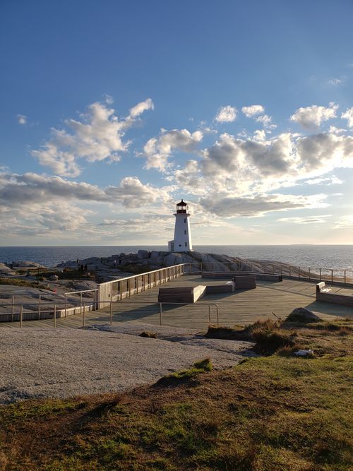 Free Beautiful day at Peggy's Cove Lighthouse with clear sky and ocean backdrop. Stock Photo
