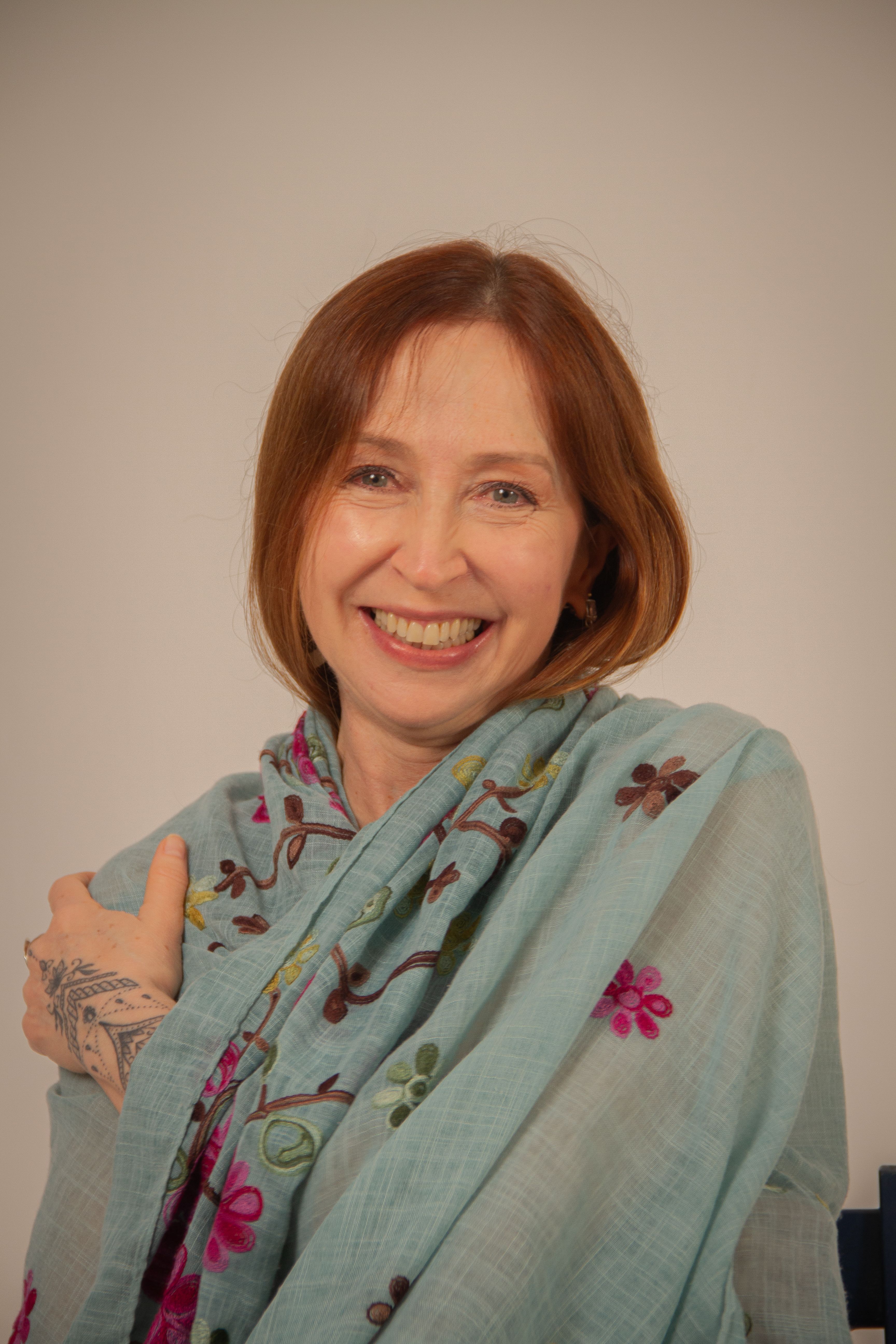 Happy woman in a floral shawl posing for a portrait, exuding warmth and contentment.