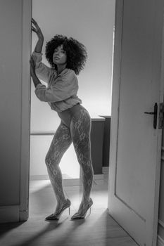 Elegant black and white photo of a woman posing in a doorway, accentuating style and grace.