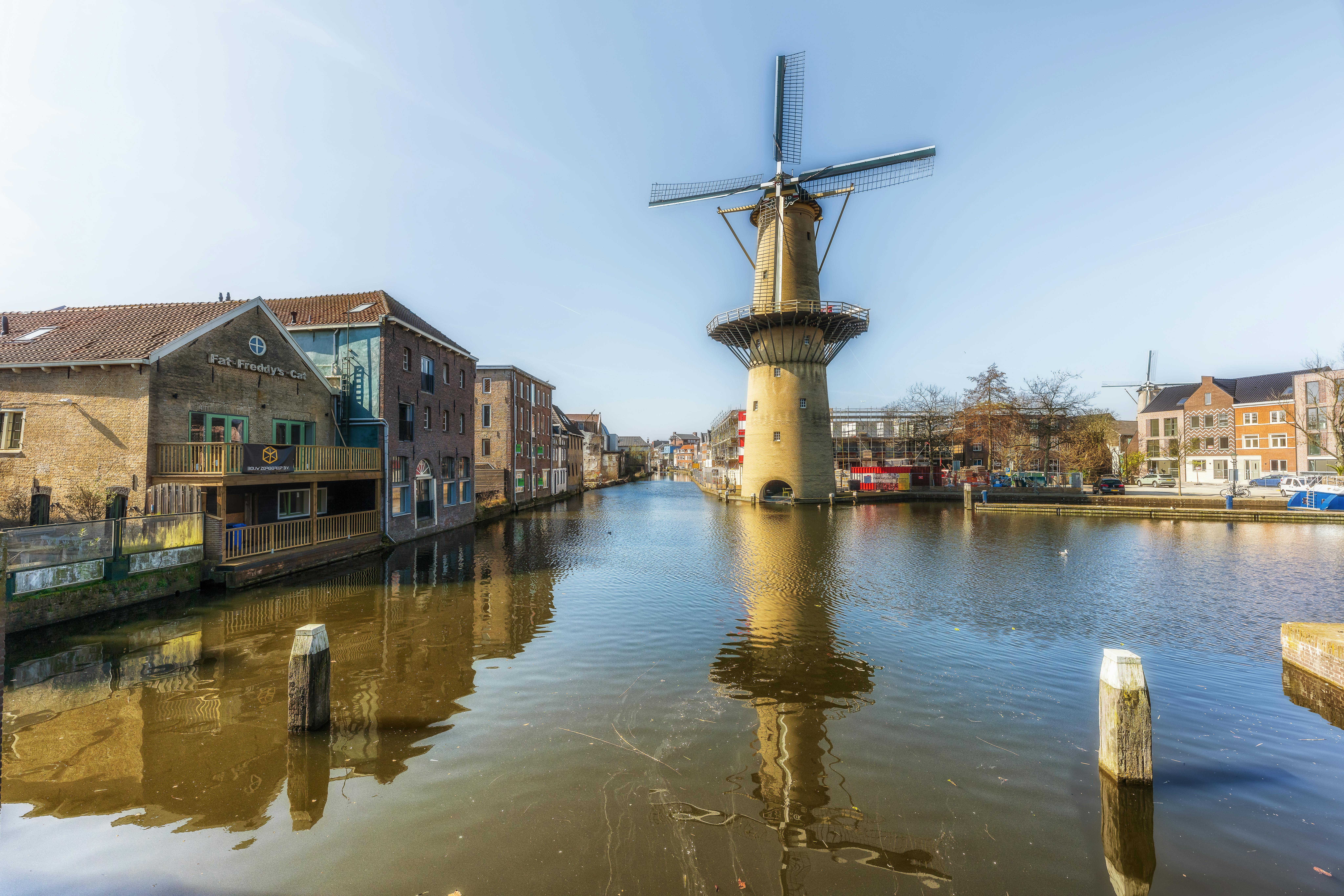 Scenic view of a windmill reflected in the canal waters in Schiedam, Zuid-Holland, Netherlands.