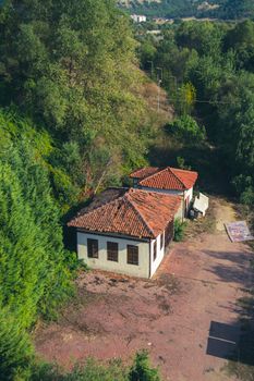 Aerial shot of a rustic house surrounded by lush greenery in a serene outdoor setting.