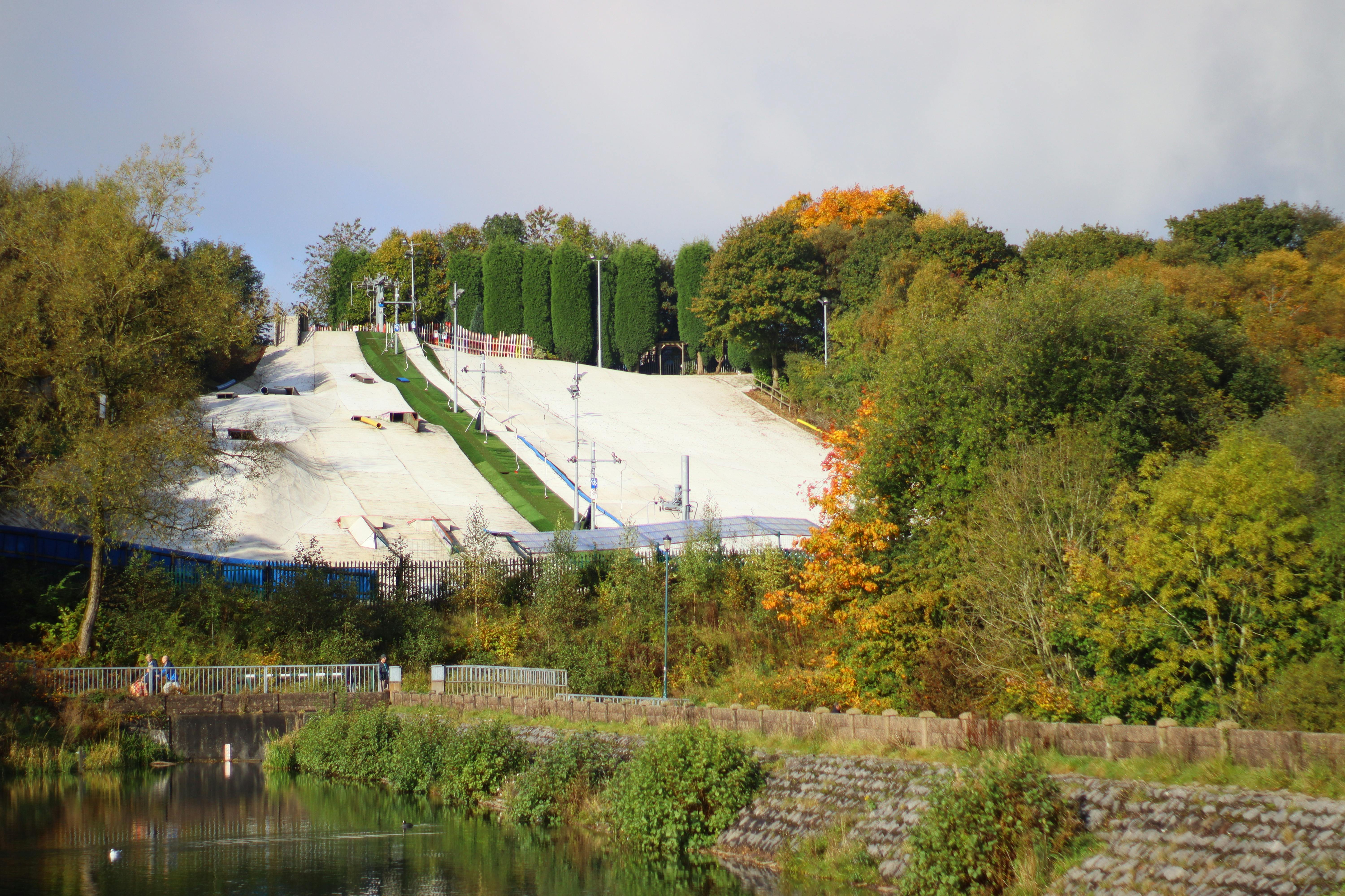 Artificial ski slope surrounded by vibrant autumn trees in England's countryside.