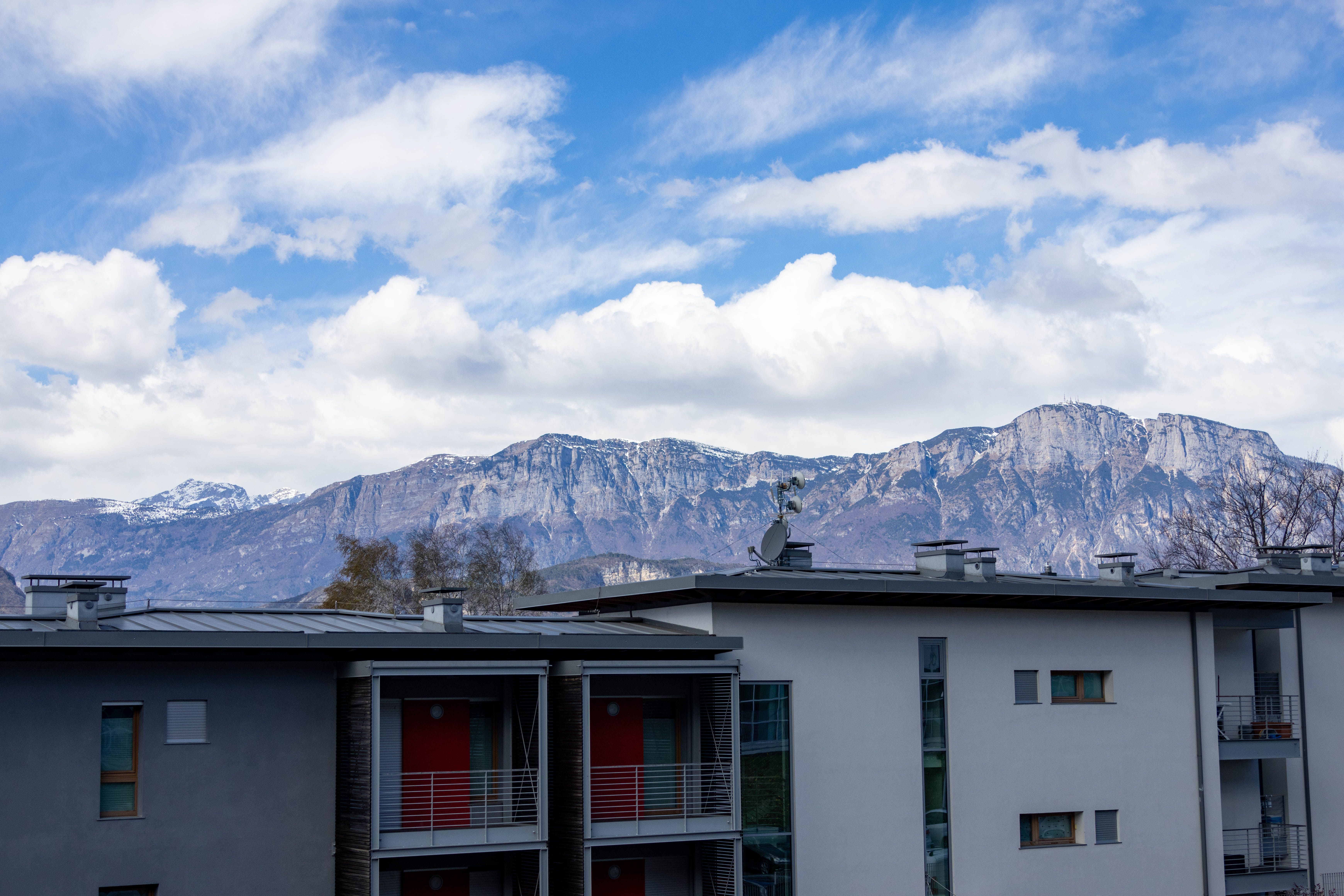 Modern building in Povo, Italy with scenic Dolomites backdrop on a sunny day.