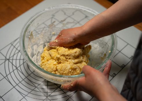 Close-up of hands kneading dough in a glass bowl, perfect for artisanal cooking and baking themes.