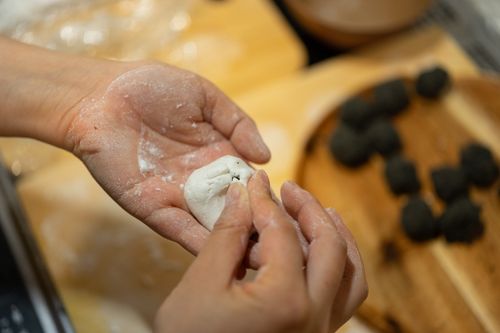 Free Hands skillfully shaping homemade dumplings on a wooden board, dusted with flour. Stock Photo