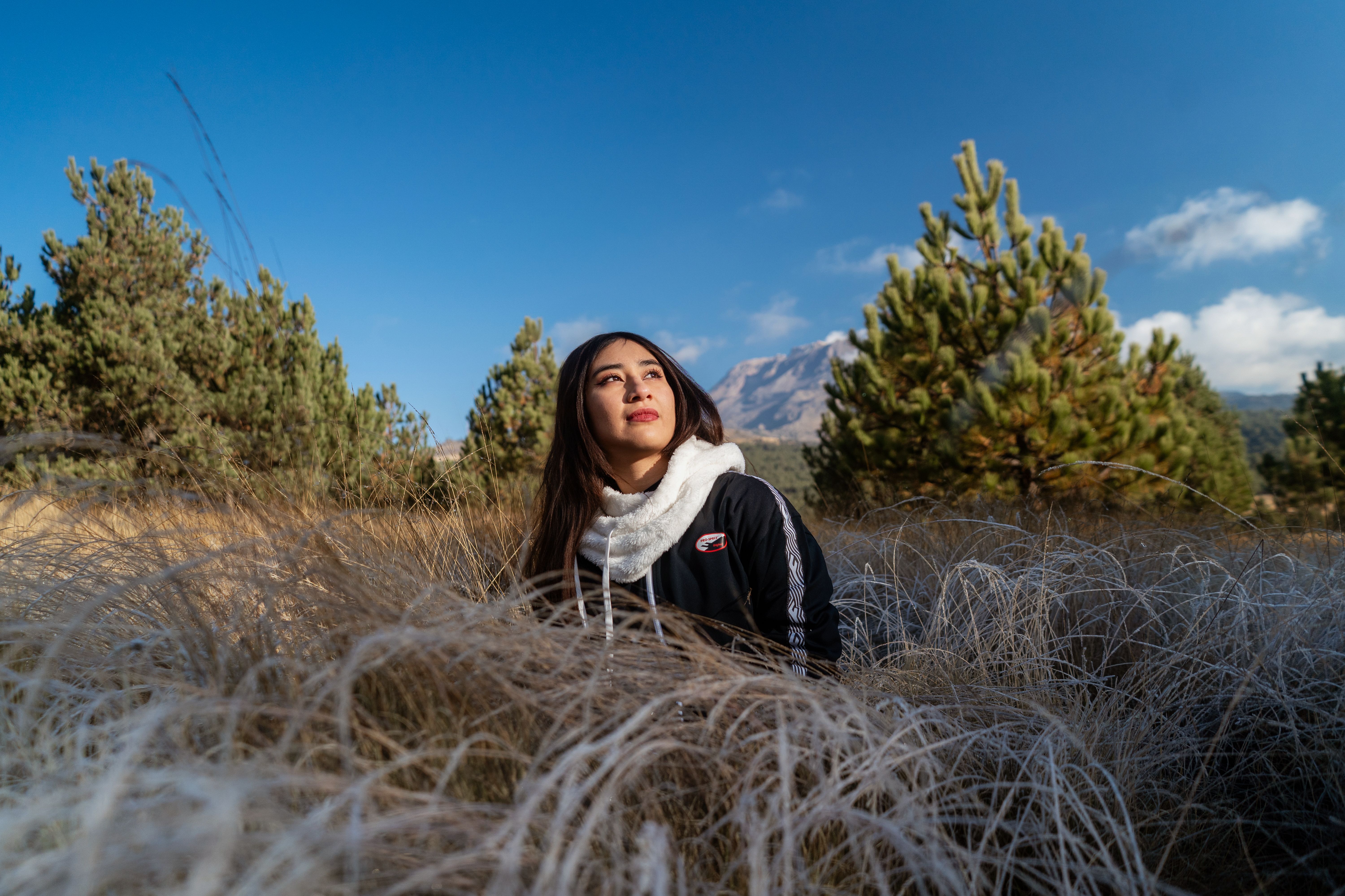 Portrait of a woman in grassy field with mountains in the background.