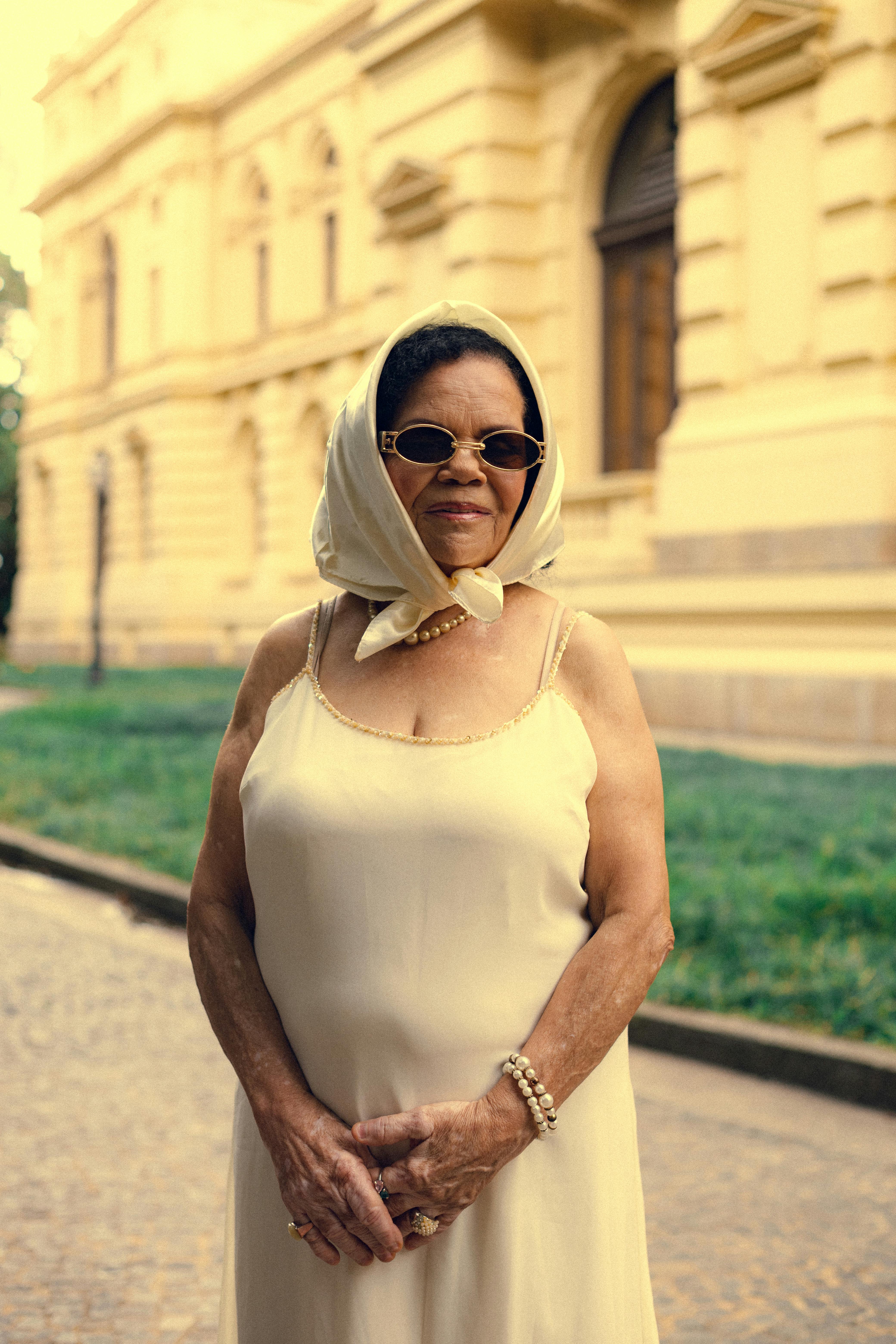 Stylish senior woman with headscarf and sunglasses posing confidently in São Paulo, Brazil.