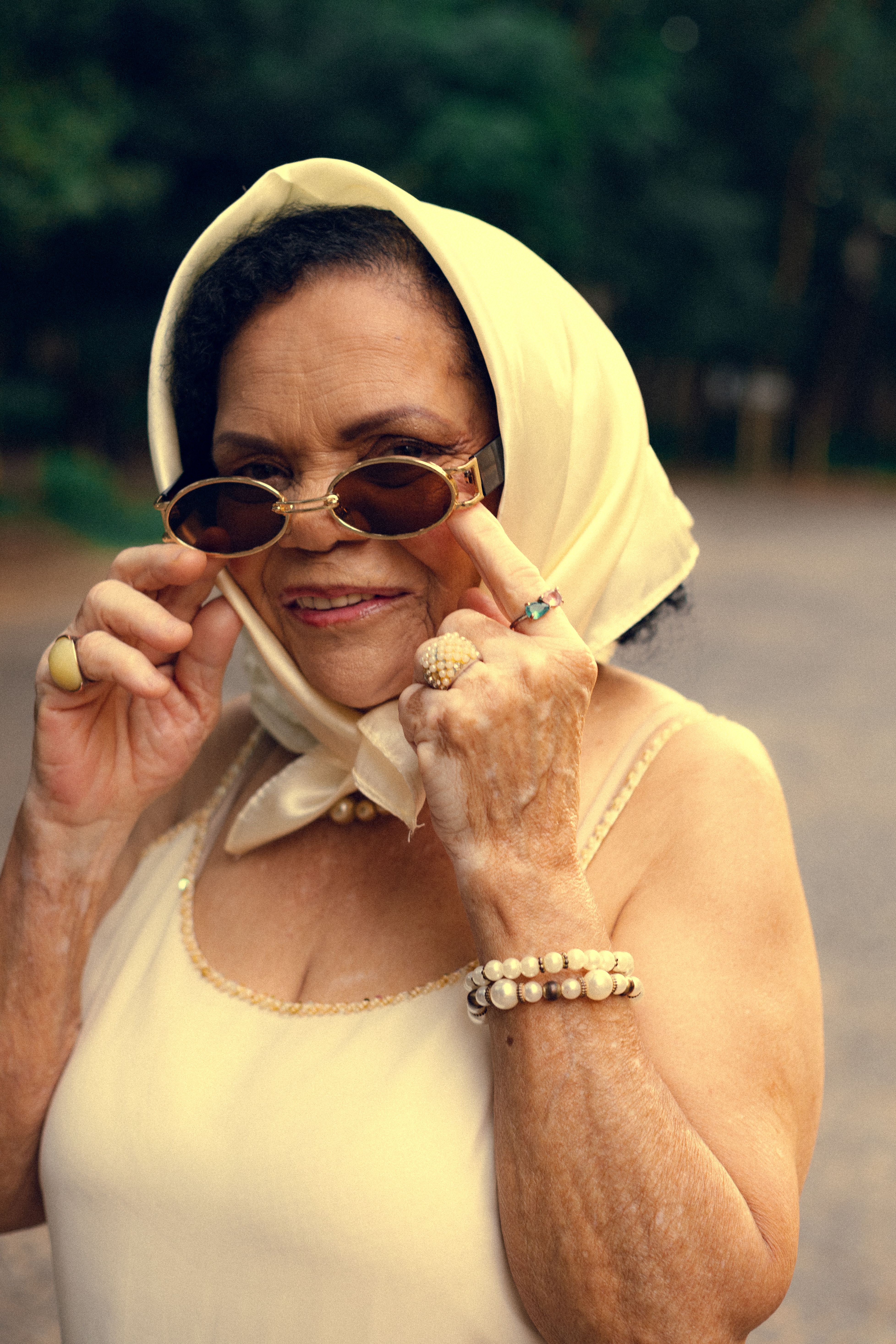 Elderly woman in São Paulo with a chic scarf and sunglasses, exuding confidence and style.