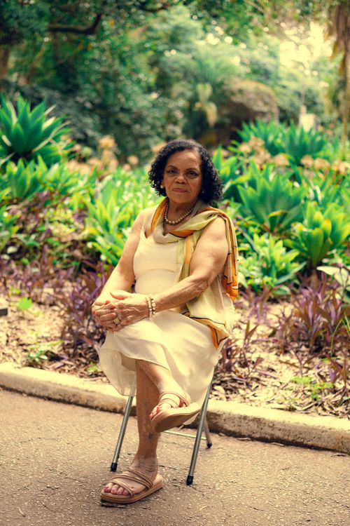 Free Elegantly dressed elderly woman sitting in a vibrant São Paulo garden, exuding calm and grace. Stock Photo