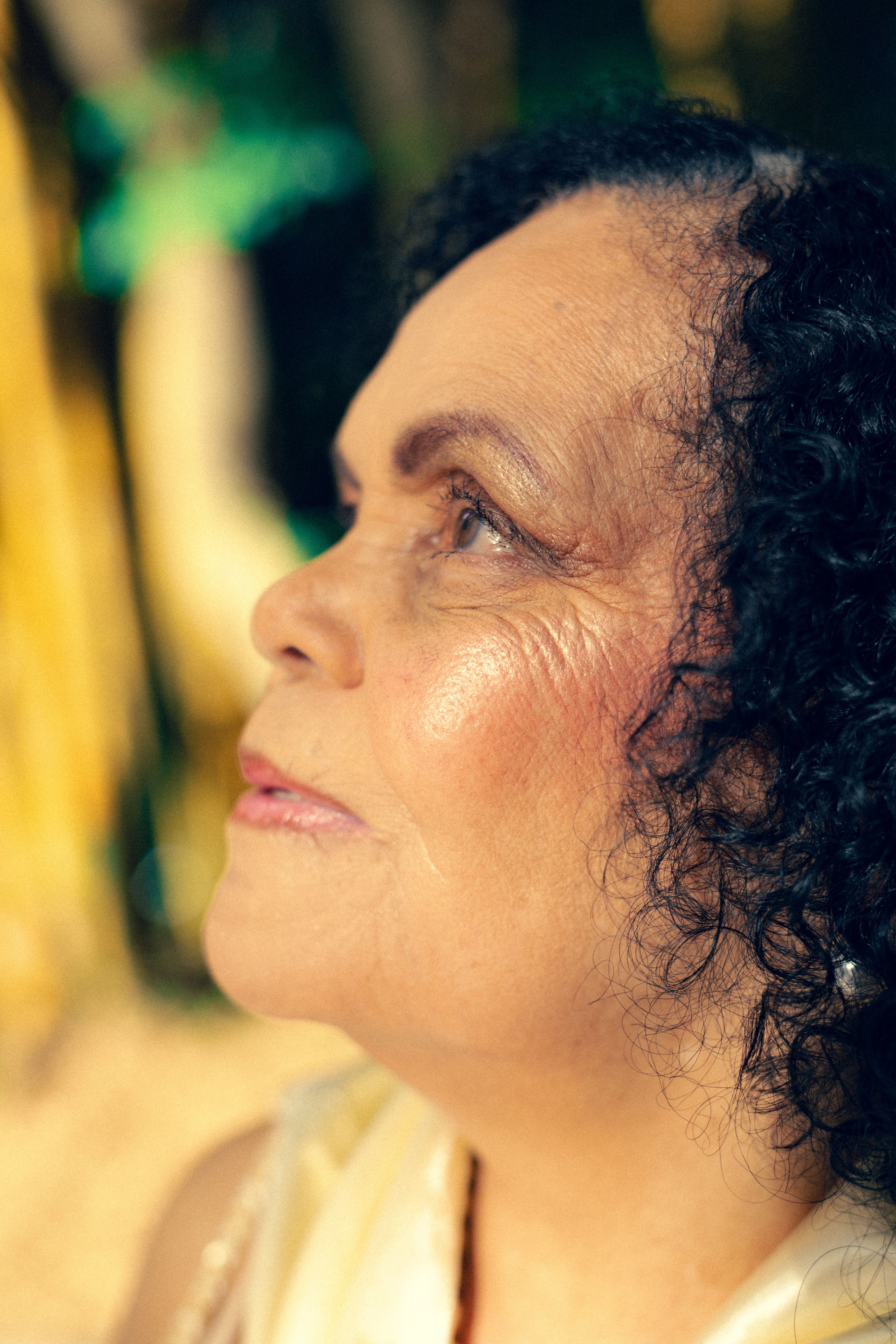 Close-up portrait of a senior woman gazing upwards, captured outdoors in São Paulo, Brazil.