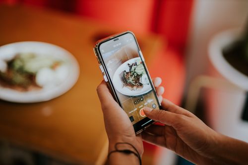 Free Close-up of a person using a smartphone to photograph food in a cozy indoor setting. Stock Photo