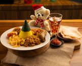Indonesian meal with a teddy bear in Christmas attire, highlighting festive dining.
