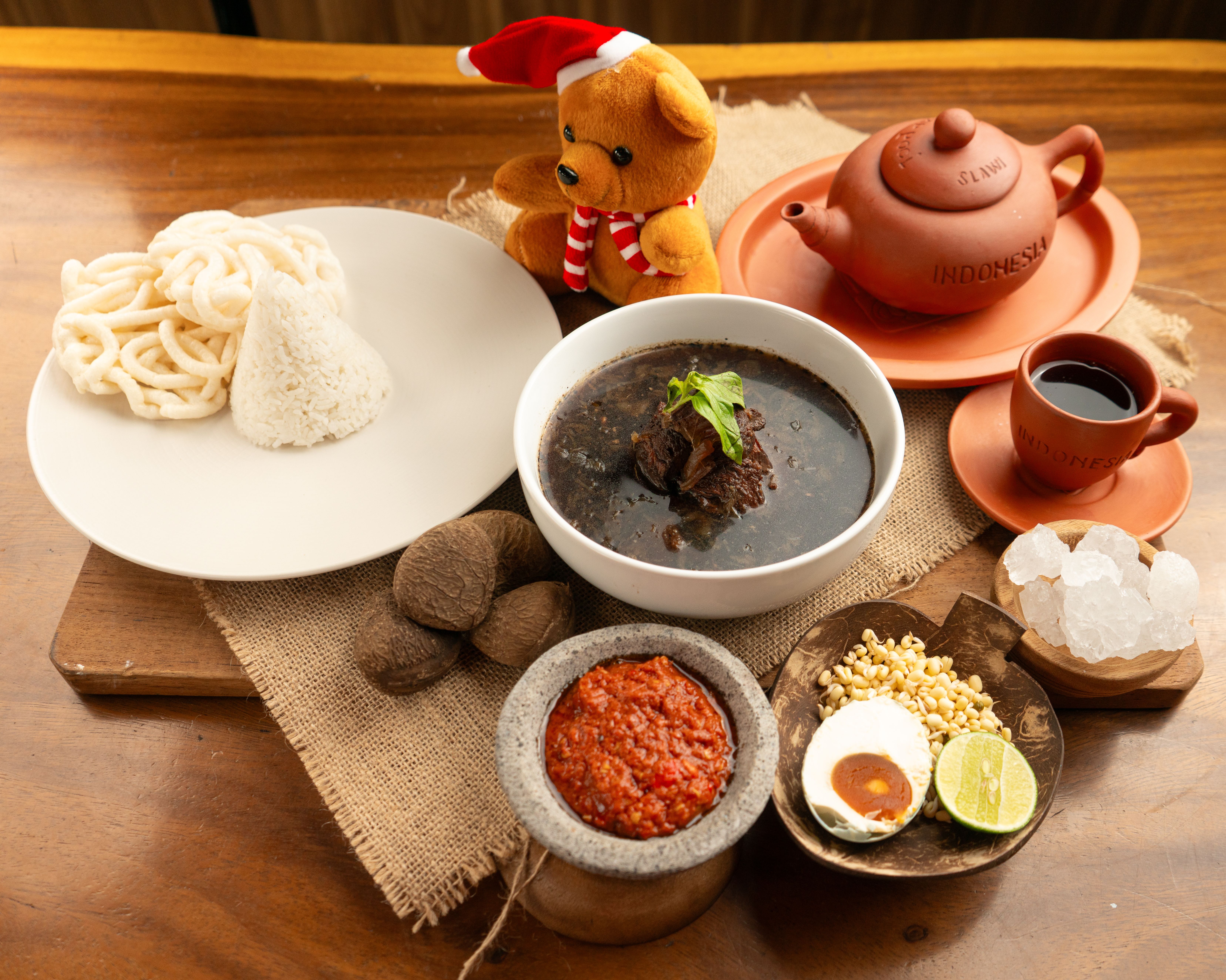 Indonesian meal setup with rawon, sambal, and traditional teakettle. Perfect for cultural and culinary themes.