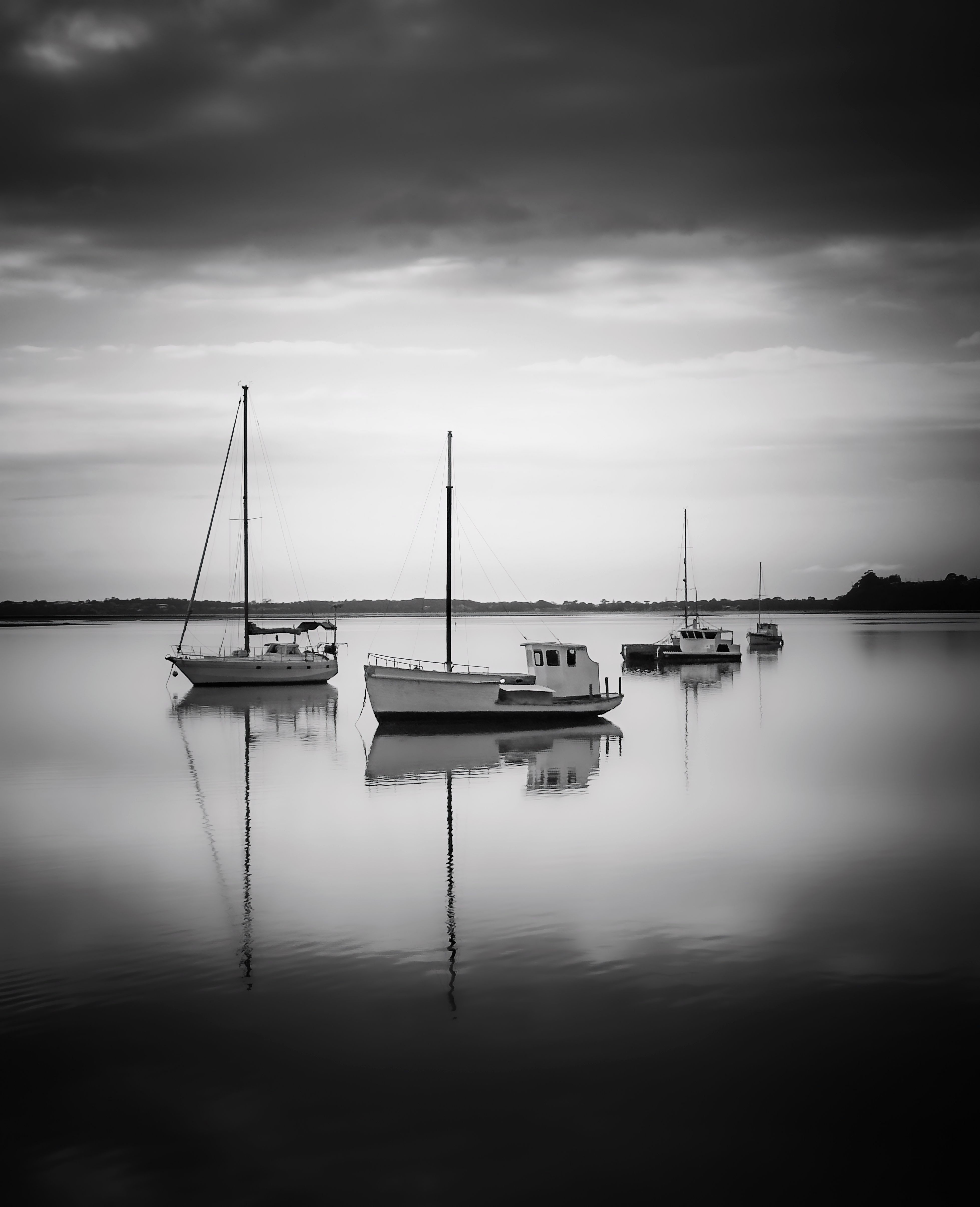 Black and white photo of boats reflecting on calm waters in St Helens, Tasmania.