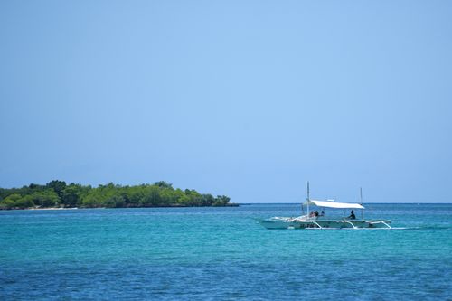 Free Scenic view of a traditional boat sailing near lush green islands in Central Visayas, Philippines. Stock Photo