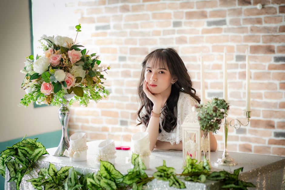 花の花束を保持している白いノースリーブのドレスの女性