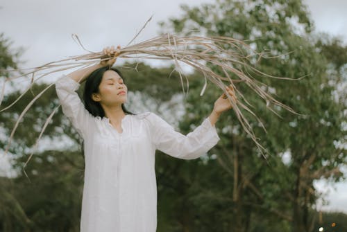 Free Woman in White Long Sleeve Holding Dry Leaves Stock Photo