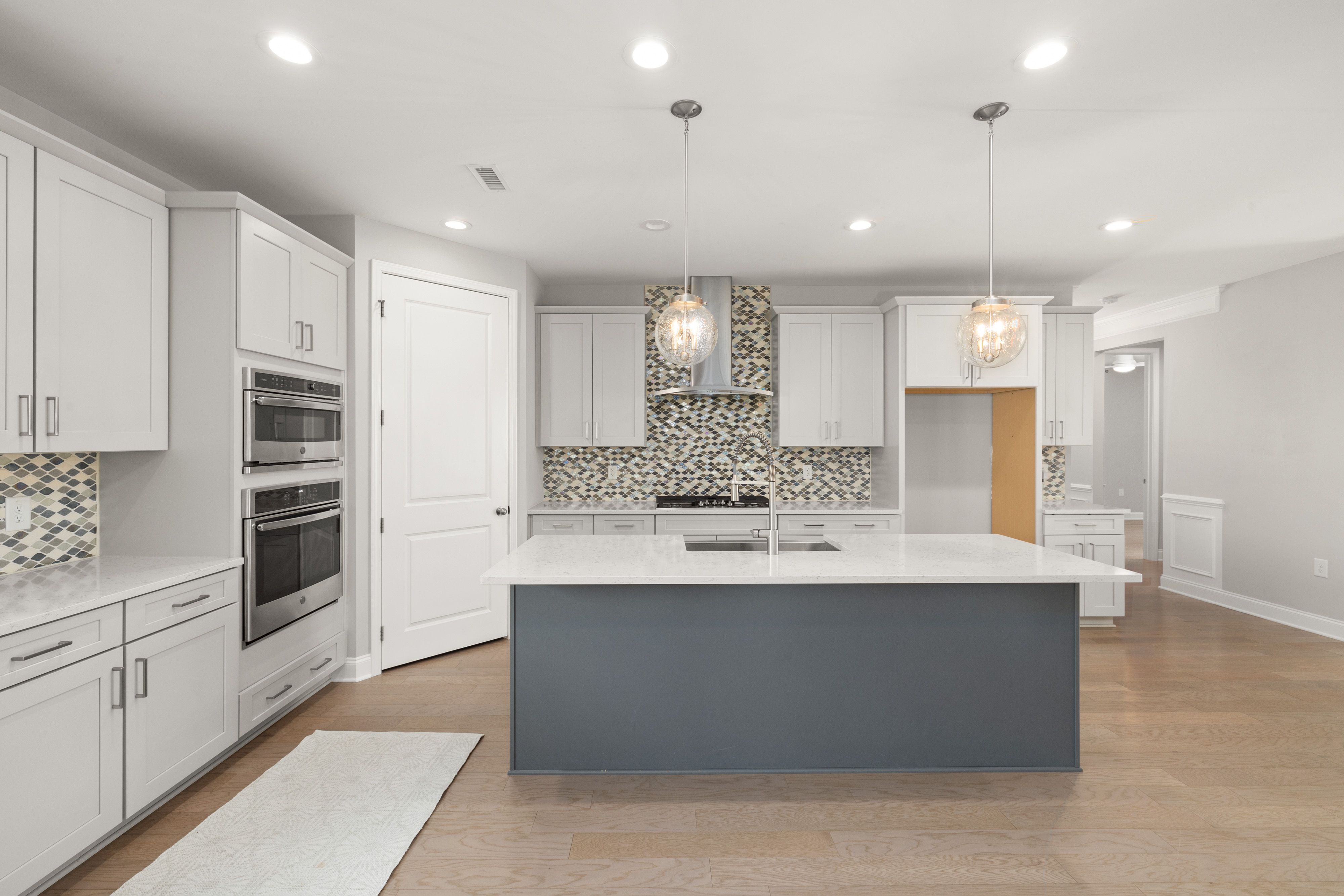 Sleek modern kitchen featuring white cabinetry, a center island, and elegant pendant lighting.