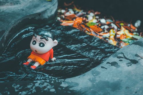 Free Toy figure of animated character in a dark water stream surrounded by fallen leaves. Stock Photo