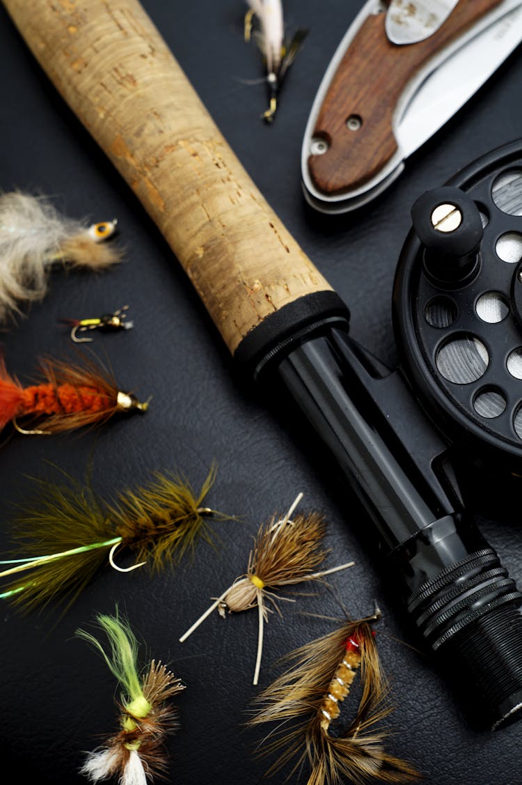 Black And Brown Fishing Rod Beside Hook And Brown Knife