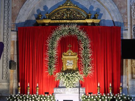 Intricate altar with gilded details and red drapery in a church in Manila, Philippines, showcasing floral decorations.
