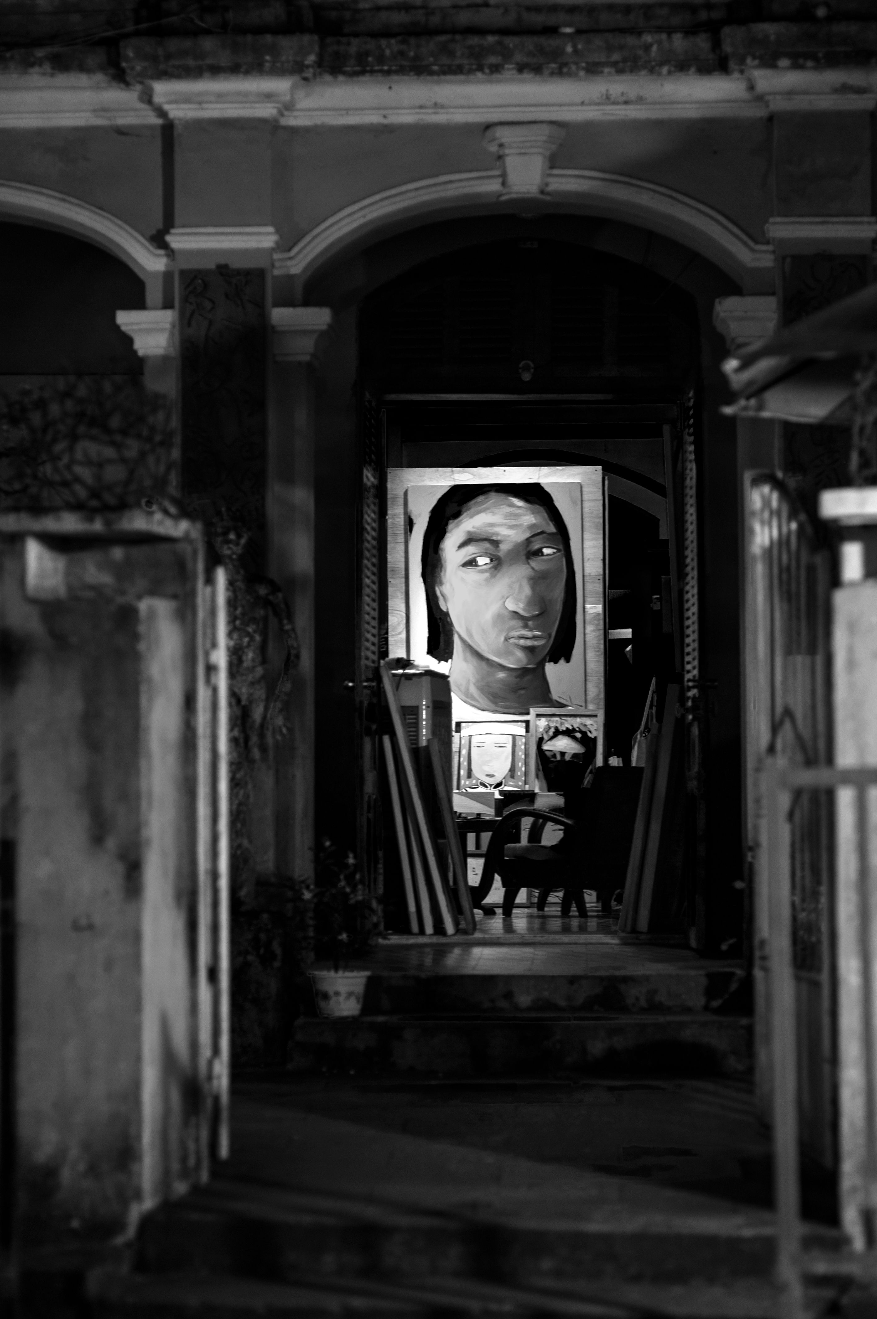 Black and white photo of a building entrance featuring a large portrait painting.