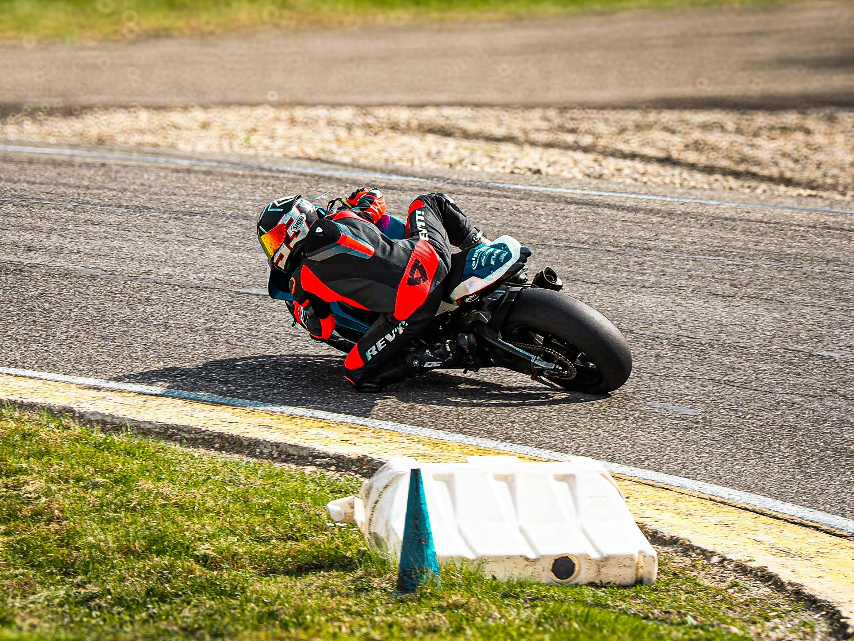 Dynamic shot of a motorcyclist wearing protective gear taking a sharp corner on an outdoor race track.