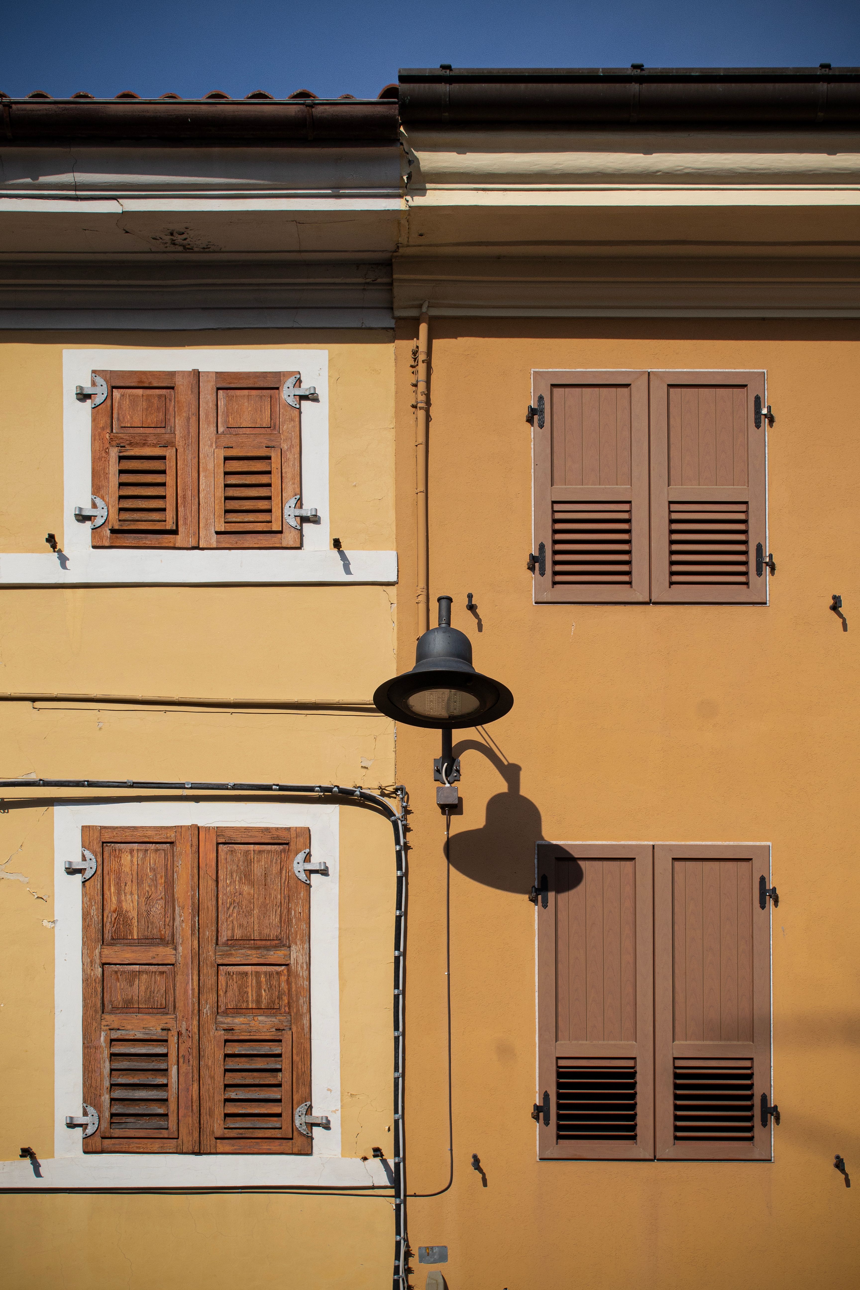 A colorful building facade in Palmanova, Italy, featuring classic wooden shutters and vibrant colors.