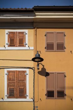 A colorful building facade in Palmanova, Italy, featuring classic wooden shutters and vibrant colors.
