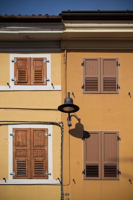 A colorful building facade in Palmanova, Italy, featuring classic wooden shutters and vibrant colors.