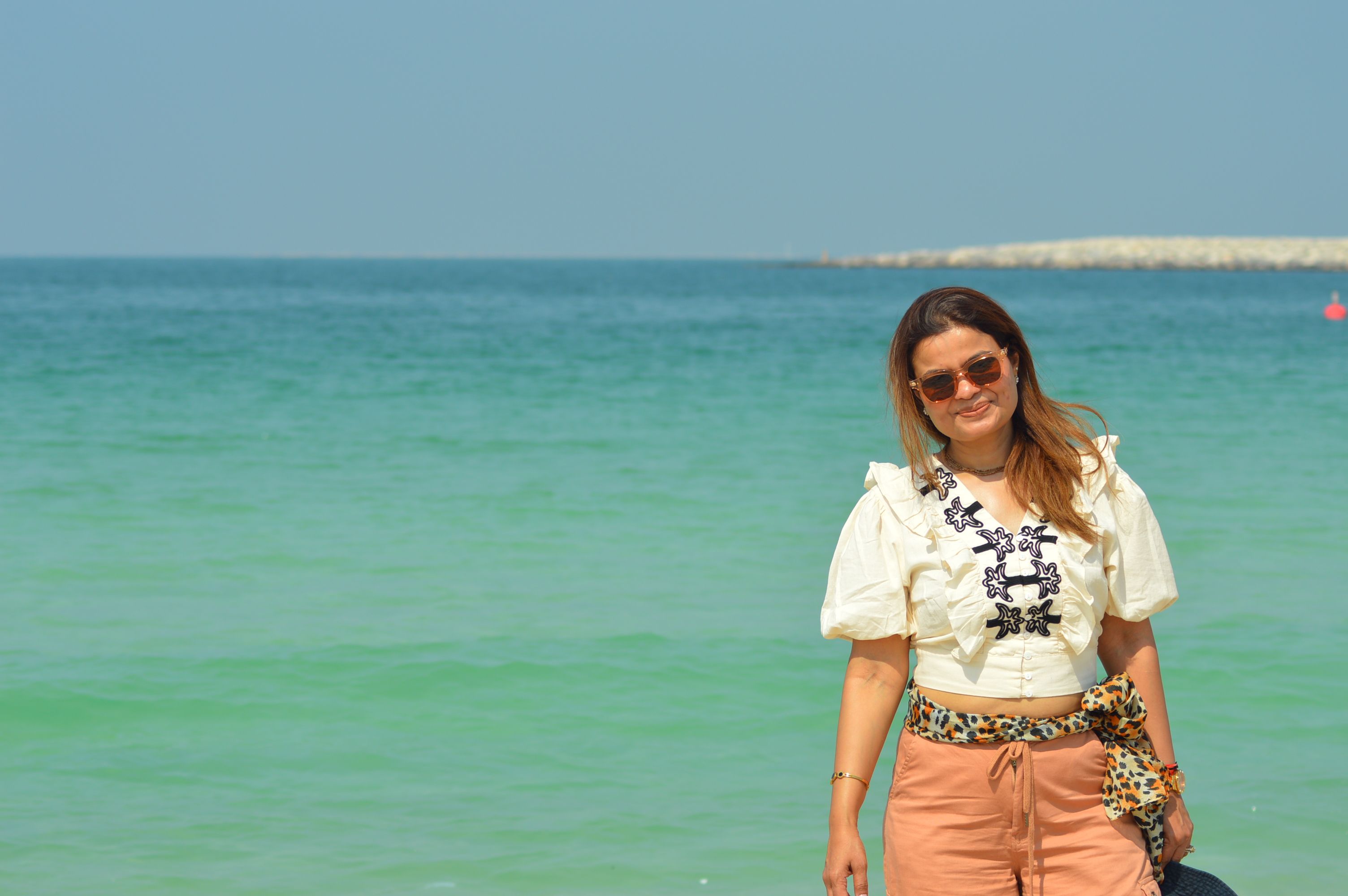 Relaxed woman smiling at the beach in Dubai under the sun.