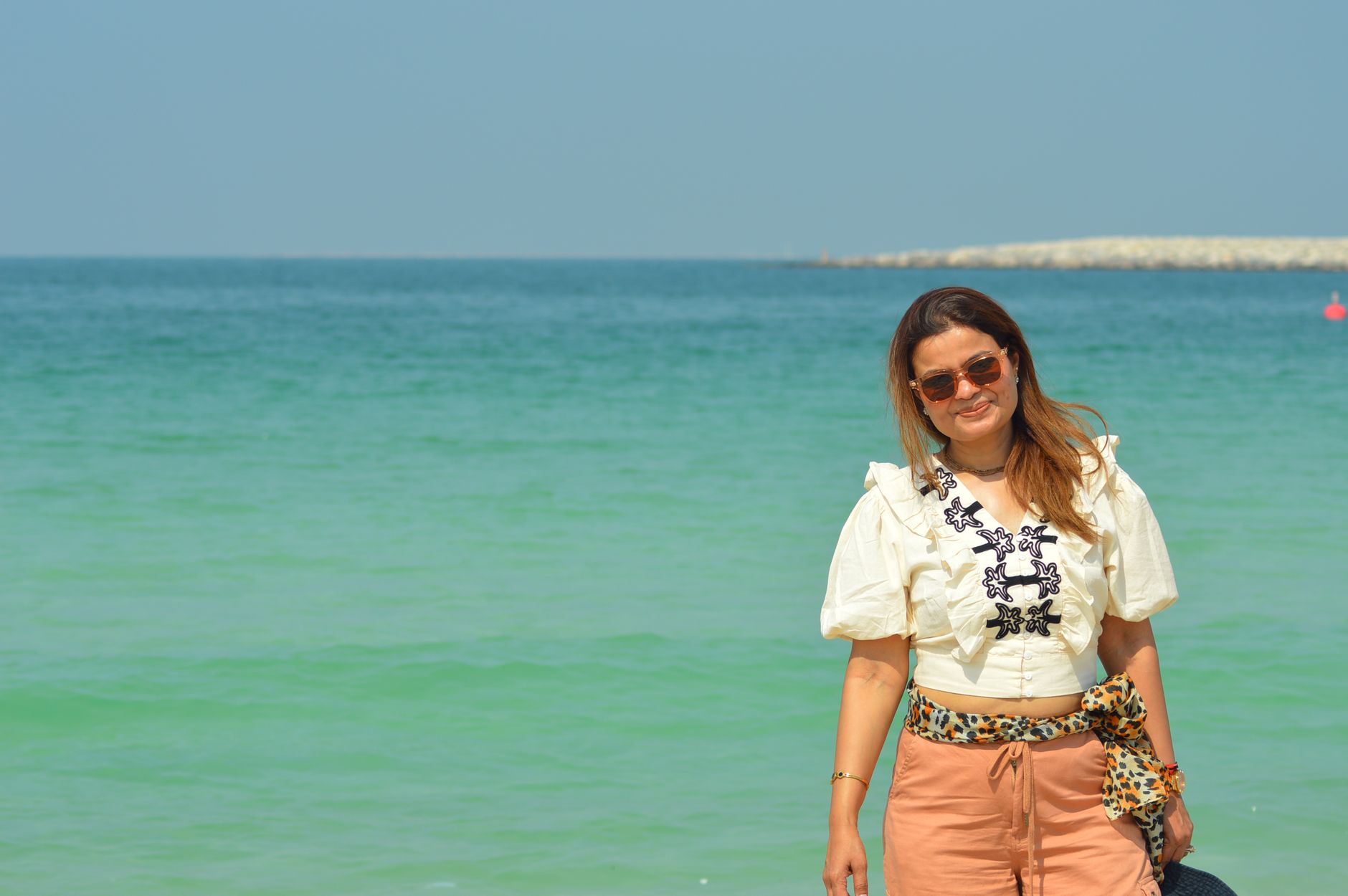 Relaxed woman smiling at the beach in Dubai under the sun.