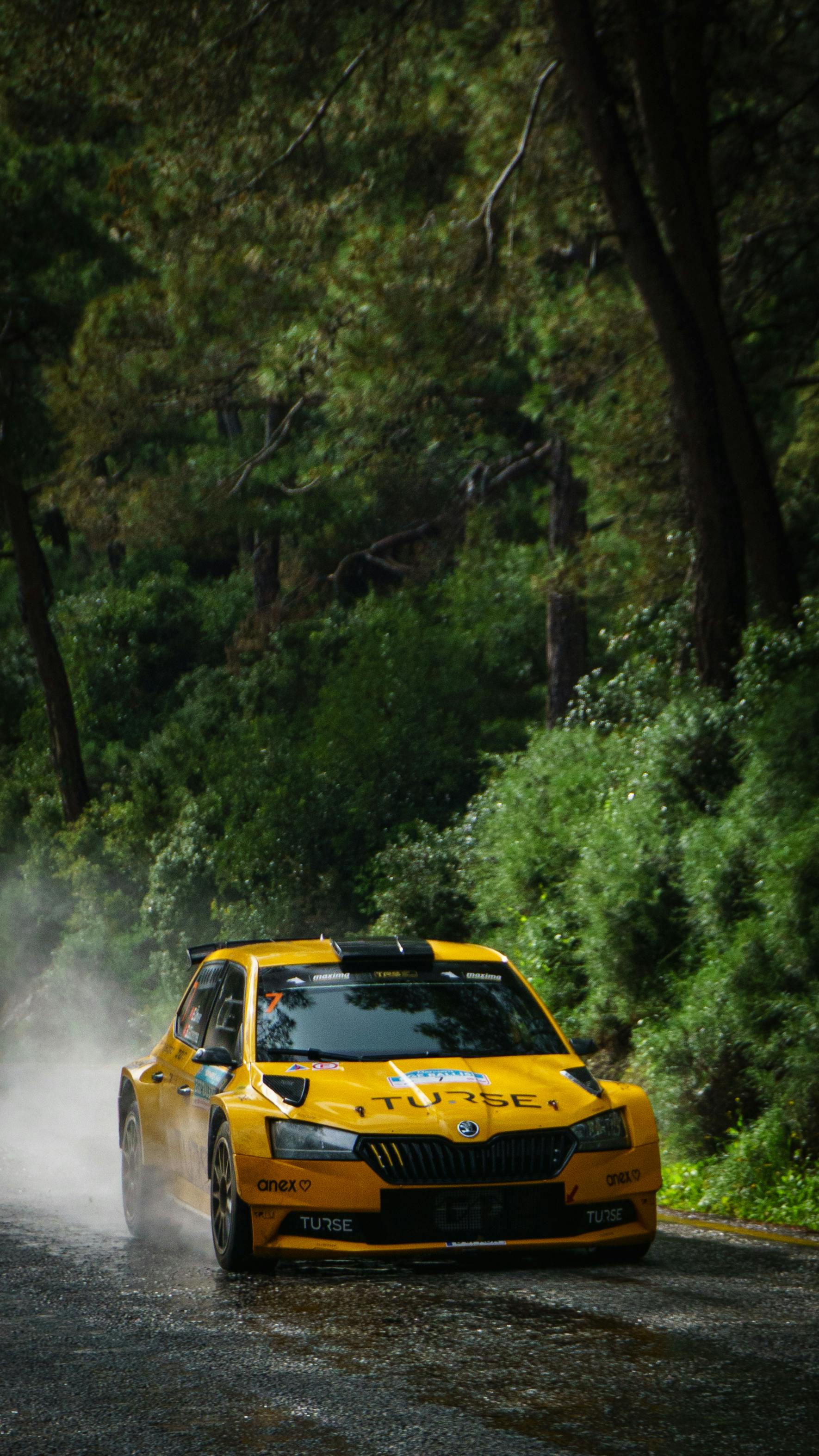 A vibrant yellow rally car speeds through a lush forest road, capturing the essence of adventure and speed.