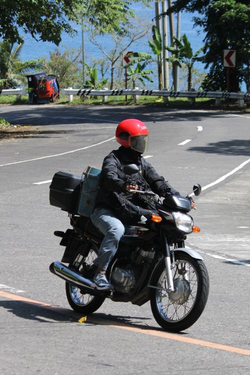 Free Rider on a motorcycle with red helmet travels a scenic coastal route under bright daylight. Stock Photo