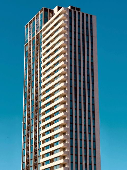 Free Tall modern skyscraper with geometric design against a clear blue sky, showcasing urban architecture. Stock Photo