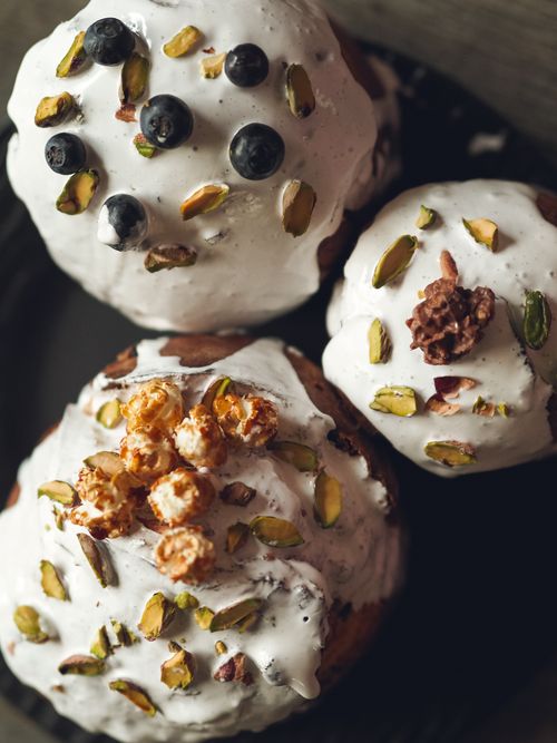 Free Delicious pastries topped with whipped cream, pistachios, popcorn, and berries on a dark plate. Stock Photo