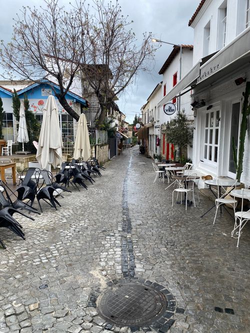 Free A picturesque cobblestone street in Çeşme, İzmir, flanked by cafes and shops. Stock Photo