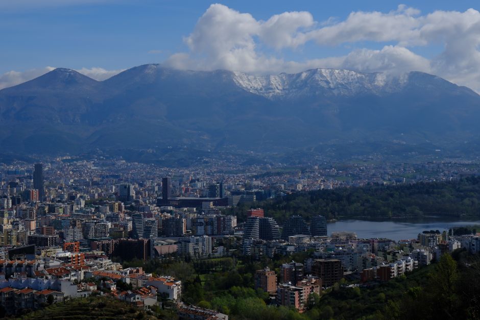 A stunning cityscape view of Tirana with Dajti Mountain in the background, under a clear sky.