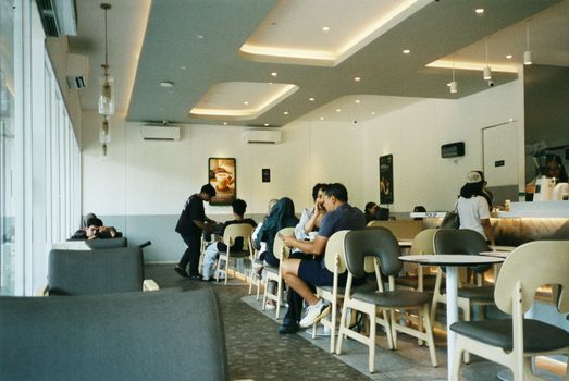 A bustling cafe in Semarang, Indonesia with people enjoying coffee and conversations.