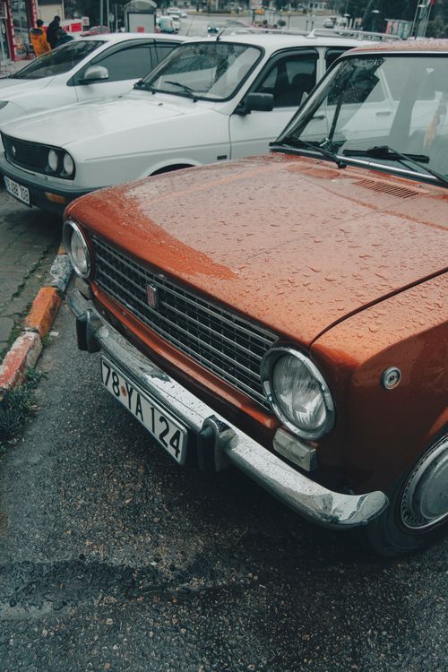 Free A vintage Fiat car with rain droplets on the hood parked outdoors. Captures nostalgic automotive charm. Stock Photo