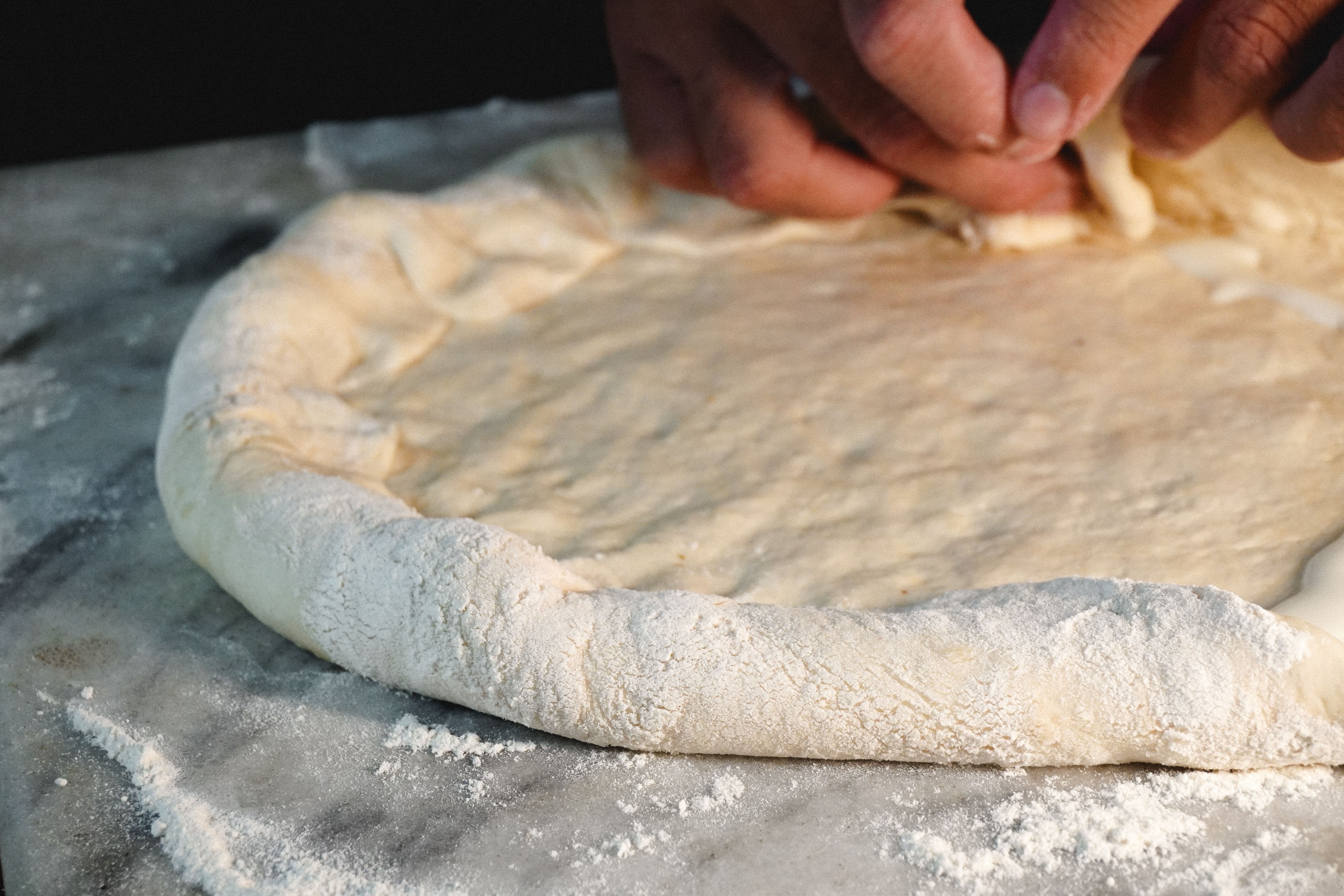 Mani che stendono l'impasto al padellino