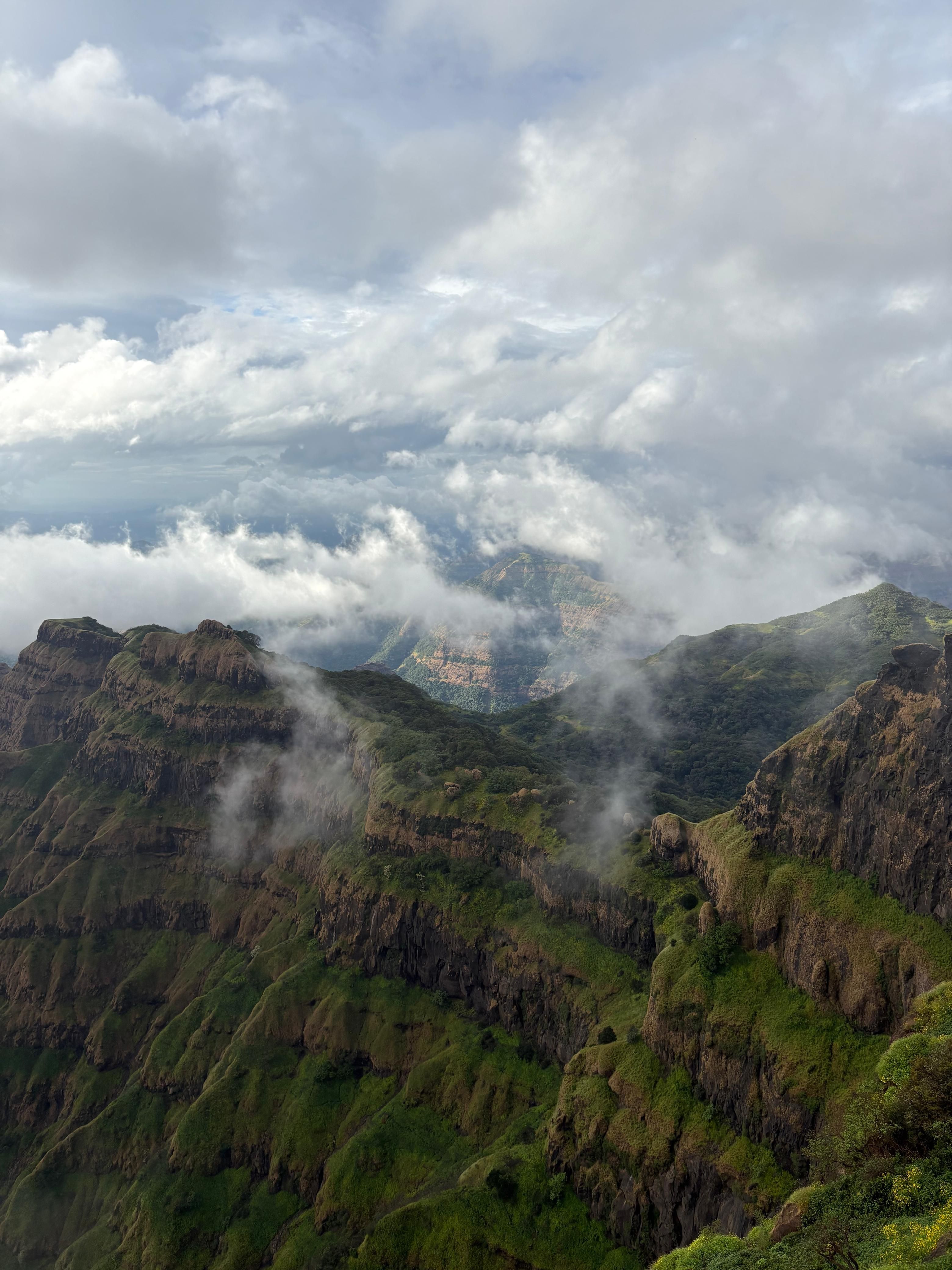 Breathtaking aerial view of lush green mountains with clouds rolling over.