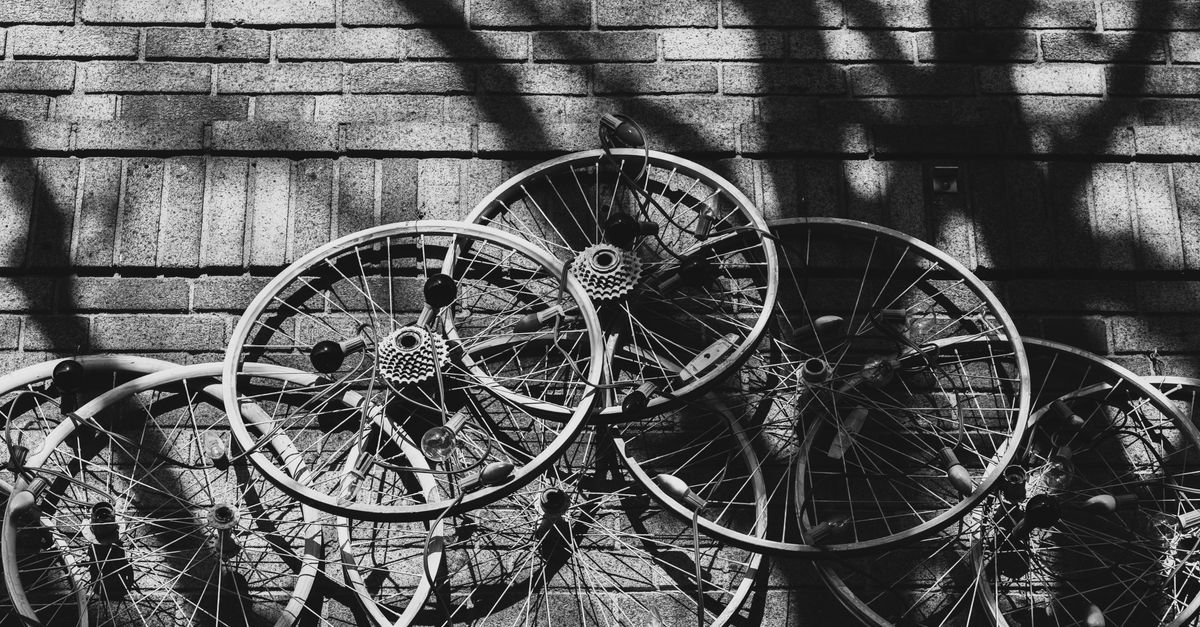 A striking black and white abstract photograph of multiple bicycle wheels against a brick wall in Somerville, Massachusetts.