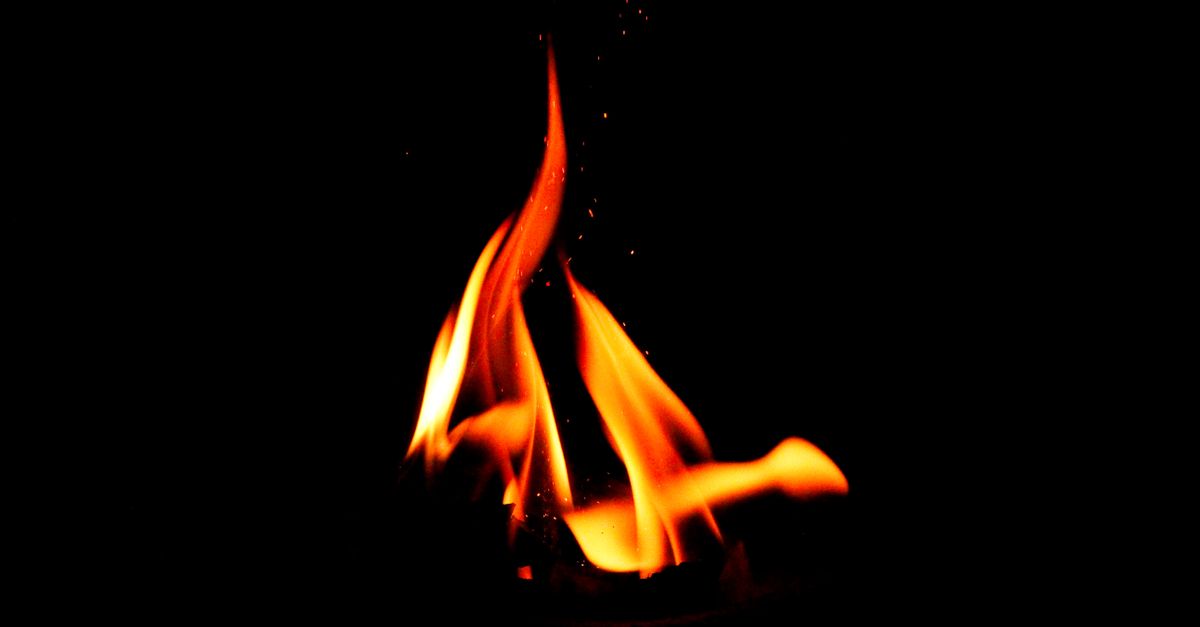 Nahaufnahme einer leuchtenden Lagerfeuerflamme vor dunklem Hintergrund