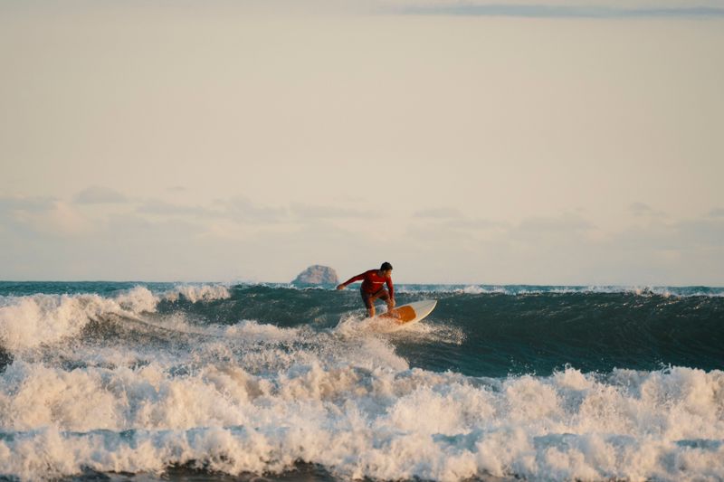 A surfer skillfully rides a wave in the ocean with a beautiful sunset
