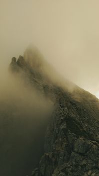 A dramatic view of rugged mountain peaks veiled by dense clouds creating a mysterious atmosphere.