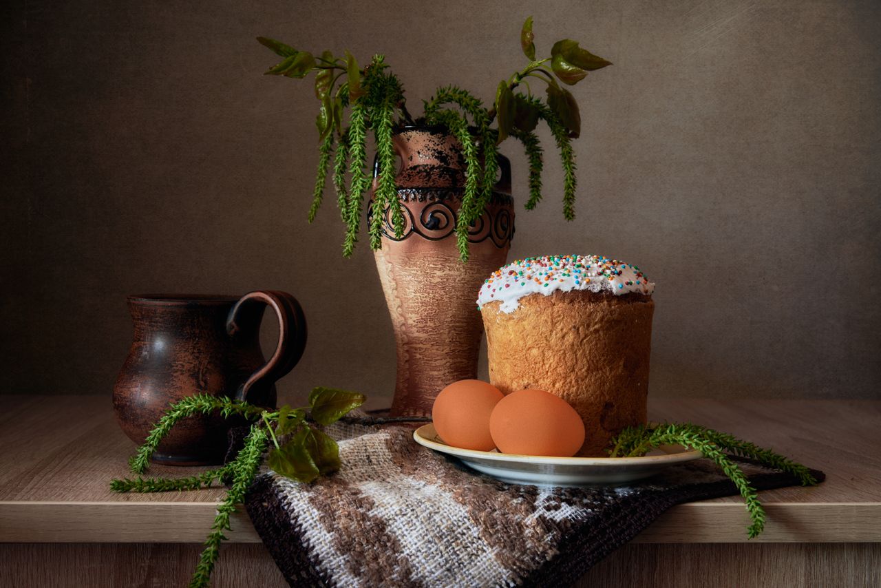 a rustic still life featuring a traditional easter cake vase and eggs